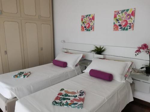 two beds in a room with white and purple pillows at Bnbook -Bilo Malpensa 3 in Gallarate