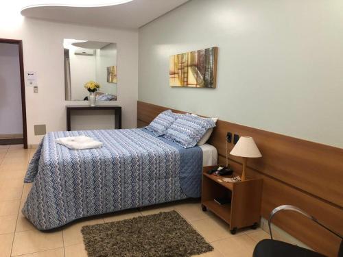 a bedroom with a bed and a table with a lamp at Buriti Hotel in Jataí