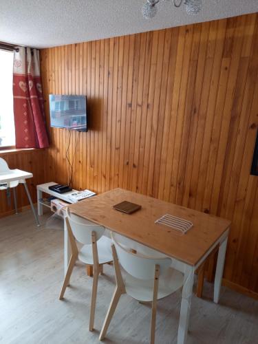 - une table et des chaises dans une chambre dotée de murs en bois dans l'établissement Studio 4 personnes centre Superbesse, à Super-Besse