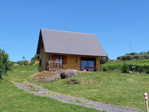 a small cabin in a grassy field with a path leading to it at Chalet Sancy in Saint-Genès-Champespe