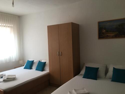 a bedroom with two beds with blue pillows and a cabinet at Apartments MAMPAS in Neum