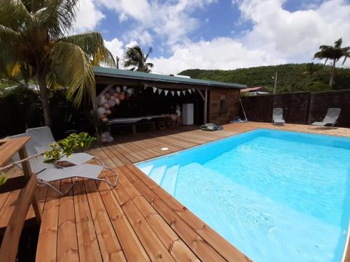 a swimming pool on a wooden deck next to a house at Kaz Madinina Colibri in Le Diamant