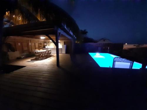 a night view of a swimming pool with a table and chairs at Kaz Madinina Colibri in Le Diamant