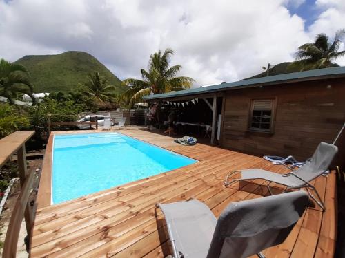 a swimming pool on a wooden deck next to a house at Kaz Madinina Colibri in Le Diamant