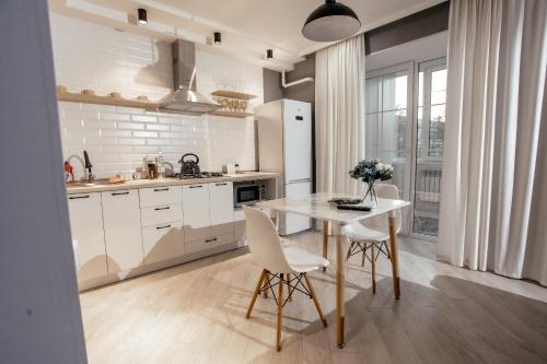 a kitchen with a white table and chairs and a kitchen with white appliances at LUX 6 МКР дизайнерская комфортная студия с панорамными дверьми и большой лоджией in Oral