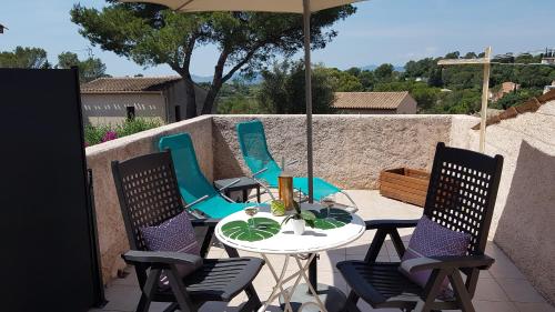 une table avec des chaises et un parasol sur une terrasse dans l'établissement Chambre d hôtes de la Louve, à Fréjus