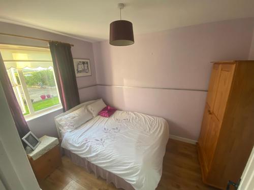 a small bedroom with a bed and a window at Primrose Cottage in Gweedore