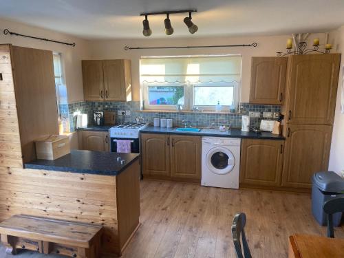 cocina con armarios de madera y lavadora en Primrose Cottage en Gweedore