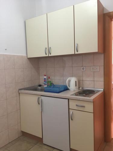 a small kitchen with white cabinets and a sink at Apartments MAMPAS in Neum