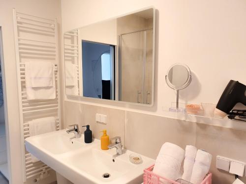 ein weißes Badezimmer mit einem Waschbecken und einem Spiegel in der Unterkunft PB Ferienwohnungen - FeWo 6 - Stilvoll eingerichtetes Apartment im Herzen Senftenbergs in Senftenberg