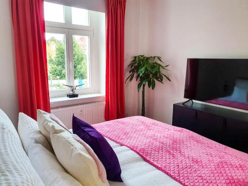 a bedroom with a bed and a window with red curtains at PB Ferienwohnungen - FeWo 6 - Stilvoll eingerichtetes Apartment im Herzen Senftenbergs in Senftenberg