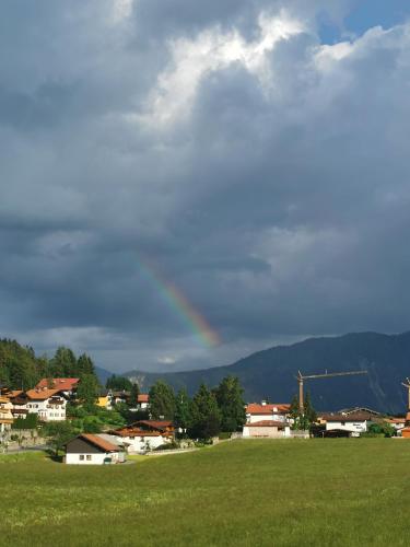 a rainbow in the sky over a green field at Haidacherhof in Eben am Achensee