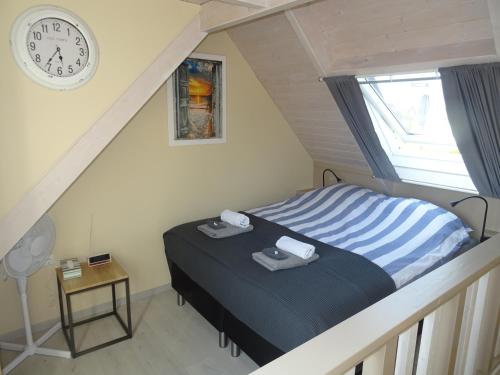 a bedroom with a bed with a clock on the wall at B&B Het Onderduukertje in Wemeldinge