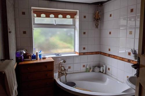 a bathroom with a bath tub and a window at Cosy 2 bed house near Peak District in Greenhill