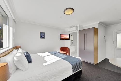 a bedroom with a bed and a desk and a television at The Hotel Nelson in Nelson