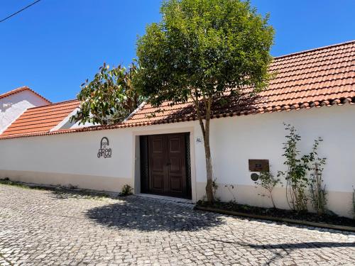 ein weißes Gebäude mit einer braunen Tür und einem Baum in der Unterkunft Casa do Arco in Abiul