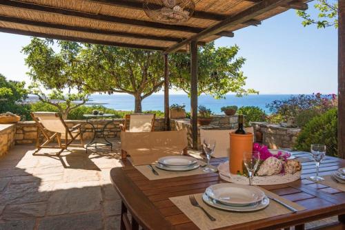 einen Holztisch auf einer Terrasse mit Meerblick in der Unterkunft Villa Venus in Avlemonas
