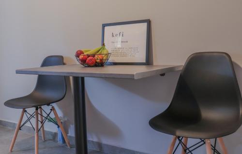 a table with two chairs and a bowl of fruit on it at Spitakia-Cozy & Comfy Apartments 10minutes from the airport in Artemida