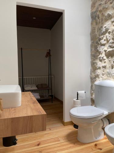 a bathroom with a white toilet and a sink at Casa do Arco in Abiul