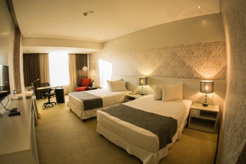 Habitación de hotel con 2 camas y escritorio en Nobile Hotel Convention Ciudad Del Este en Ciudad del Este