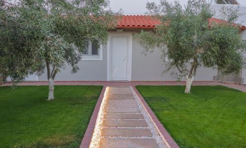 a house with a white door and two trees at Spitakia-Cozy & Comfy Apartments 10minutes from the airport in Artemida