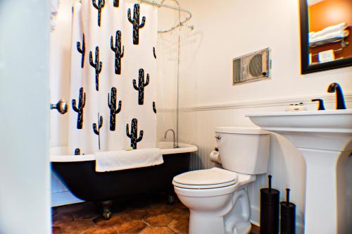 a bathroom with a toilet and a cactus shower curtain at Eldorado Suites Hotel in Bisbee
