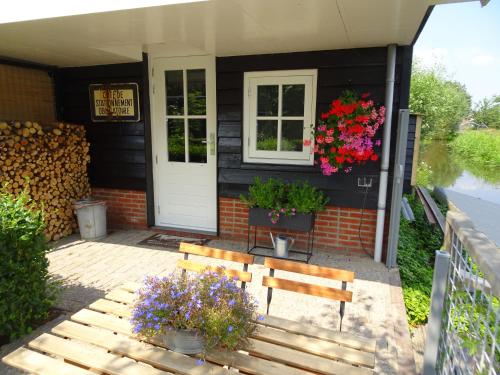a house with two benches and flowers in front of it at De Kopstoof in Lekkerkerk