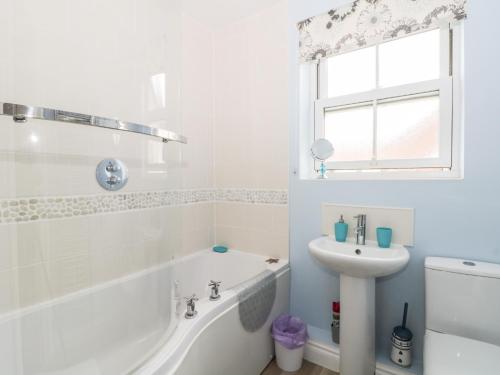 een witte badkamer met een bad en een wastafel bij Nett's Coastal Escape in Filey