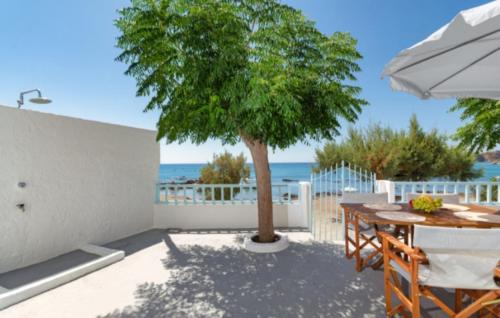 a patio with a table and a tree and the ocean at Casa al mare in Archangelos