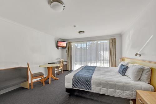a bedroom with a bed and a table and a window at The Hotel Nelson in Nelson