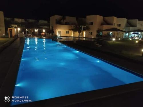 Maxaranguape的住宿－PARAÍSO DE MARACAJAÚ - BEIRA MAR，夜间拥有蓝色灯光的游泳池