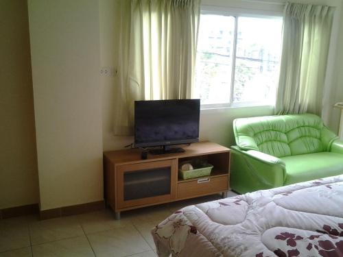 a living room with a television and a chair at Vanlisut Hotel Ngamwongwan in Nonthaburi