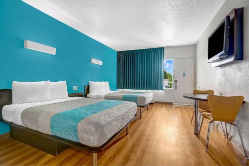 Habitación de hotel con cama, mesa y TV. en Motel 6-Jacksonville, NC, en Jacksonville