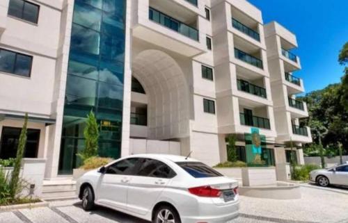 ein weißes Auto, das vor einem Gebäude geparkt ist in der Unterkunft Apartamento Decorado na Serra em Itaipava in Petrópolis