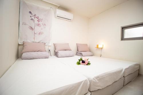 a white bed with a bouquet of flowers on it at YAB-GuestHouse, FemaleOnly, ForeignOnly in Seoul