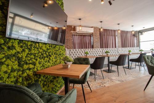 a restaurant with a green wall with tables and chairs at OASIS Apartments in Gevgelija