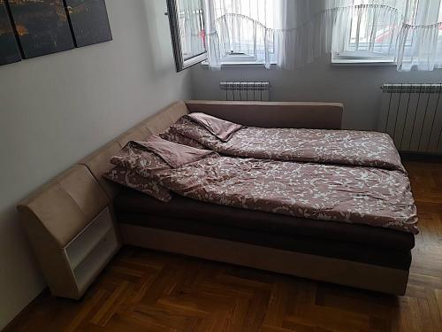 uma cama não feita num quarto com pisos em madeira em Belgradian 011 em Belgrado