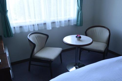 a room with two chairs and a table and a bed at Highland Furano in Furano