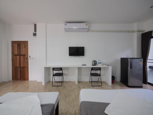 a bedroom with two beds and a desk with a tv at Prukpibul Apartment in Bangkok