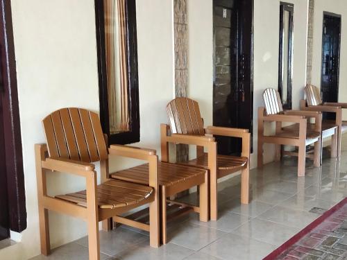 a row of wooden chairs sitting next to a wall at penginapan karanglaut santolo in Cilauteureun