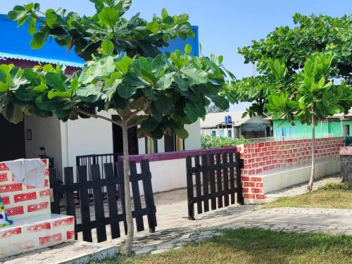 a black fence with a tree in front of a house at penginapan karanglaut santolo in Cilauteureun