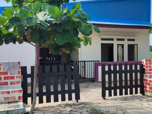 a house with a black fence and a tree at penginapan karanglaut santolo in Cilauteureun