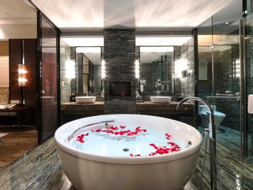 un baño con una bañera con flores rojas. en Shenzhen Baohengda International Hotel, en Longgang