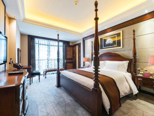 a bedroom with a large bed with a desk and a desk at Shenzhen Baohengda International Hotel in Longgang