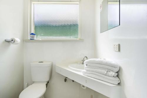 een badkamer met een toilet, een wastafel en een raam bij Top of the Town Hotel Motel in Burnie