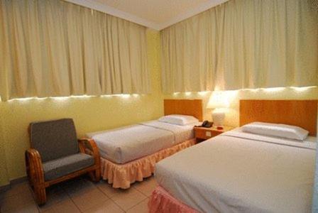 a hotel room with two beds and a chair at Hotel City View in Sandakan