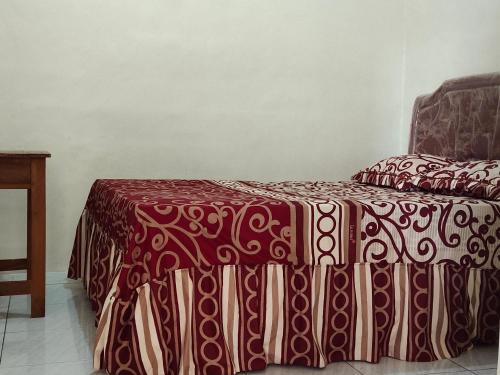 a bed with a red and brown blanket on it at penginapan karanglaut santolo in Cilauteureun