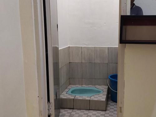 a bathroom with a shower with a blue tub at penginapan karanglaut santolo in Cilauteureun