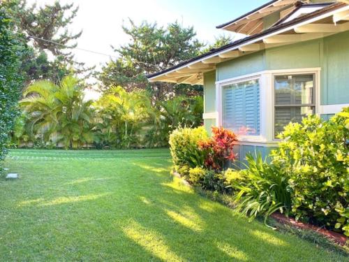 Modern Luxury Beach House Kailua في كايلوا: منزل مع فناء مع العشب الأخضر والزهور