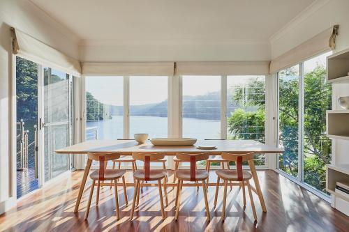 a dining room with a table and chairs and a large window at Calabash Bay Lodge in Berowra